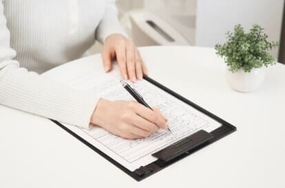 受付・問診表の記入をしている女性の画像